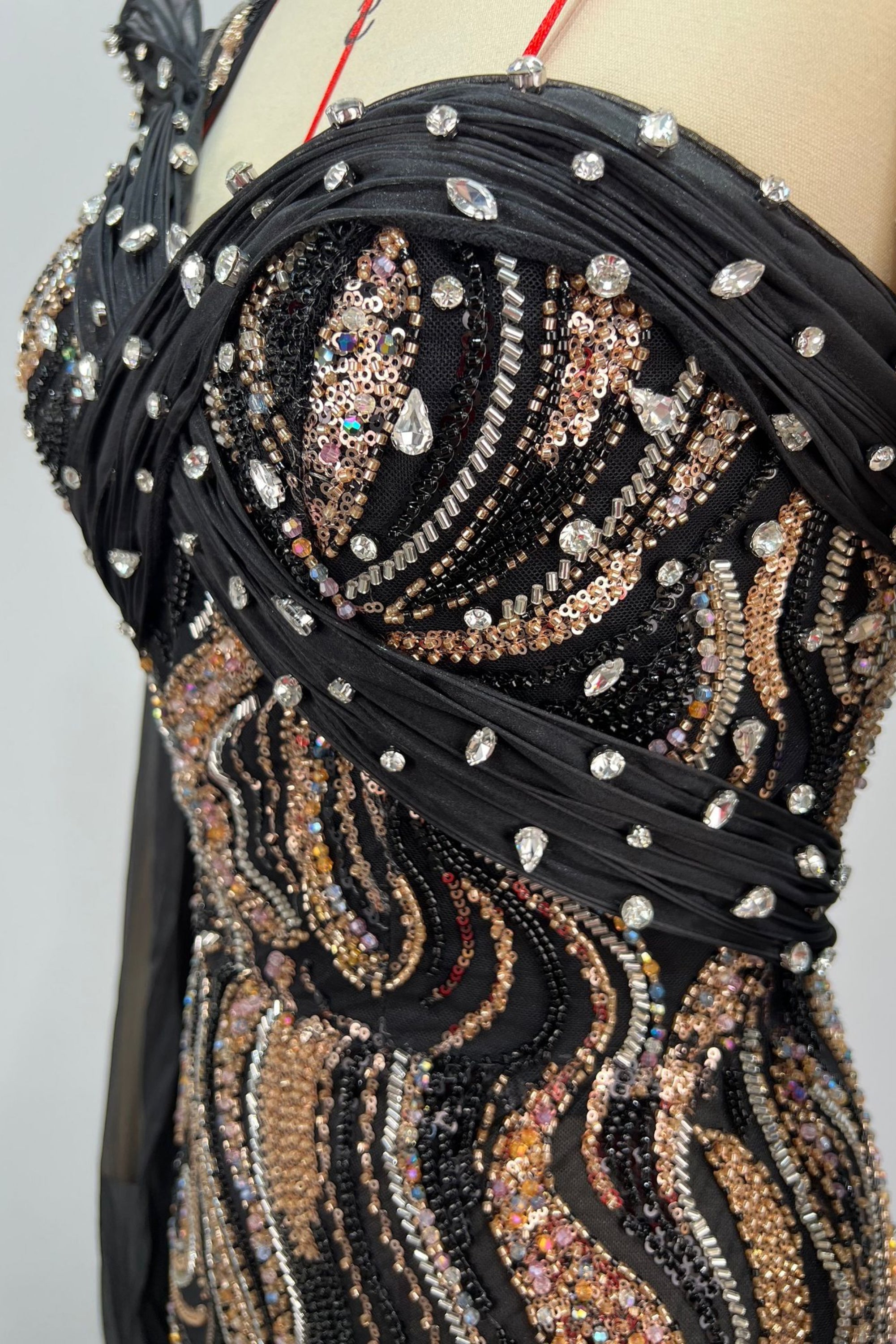 Decorative black and gold garment with intricate patterns and embellishments on a mannequin.